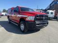 A red 2015 RAM 2500 pickup truck with a black grille and a truck bed cap, parked in the foreground