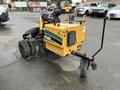 A yellow and black 2014 Vermeer Corporation Sweep Stump Cutter with large rear wheels and a front-mounted grinding attachment