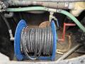 A blue hose reel with coiled black hoses is positioned in a compartment of a 2018 Kenworth T800 truck