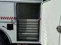 A 2010 International 4300 truck with an open storage compartment featuring multiple metal shelves for organizing equipment and supplies