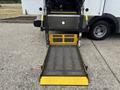 A foldable wheelchair ramp with a textured surface and yellow edges, standing upright next to a 2020 Chevrolet Express van