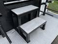 A pair of black metal steps with a diamond plate design arranged in a stacked formation on a truck platform