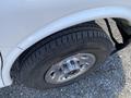 Close-up of a wheel and tire from a 2023 GMC Savana showing shiny chrome hubcap and textured tire tread