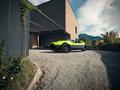 A bright green 2024 Vanderhall Carmel sports car with a sleek design and convertible top parked on gravel near a modern building