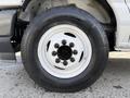 Close-up of a white wheel and tire on a 2023 Ford E-450 featuring multiple lug nuts and a treaded tire profile