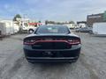 A rear view of a black 2015 Dodge Charger with sleek taillights and the Dodge logo prominently displayed across the trunk
