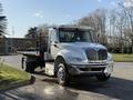 A 2017 International 4300 flatbed truck with a silver body and black accents, featuring a cab with a distinctive grille and multiple lights on the roof