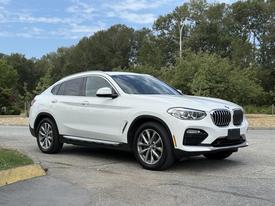 A white 2019 BMW X4 parked with a sporty design featuring a sleek body, prominent kidney grille, and alloy wheels