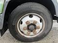 Close-up of the rusted wheel and tire of a 2012 Mitsubishi Fuso FE showing the lug nuts and treads of the tire