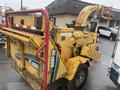 A yellow 2010 Vermeer Corporation BC1000XL wood chipper with a red safety bar attached and various control levers visible on the side