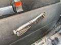 A metallic door handle of a 1996 GMC Top Kick truck with a lever design and a textured grip