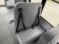 A gray seat with black safety straps designed for a passenger in a van or bus