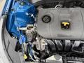 A 2021 Kia Forte engine with black plastic cover and yellow coolant cap visible along with various engine components and hoses