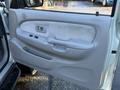 The image shows the interior door panel of a 2004 Toyota Tacoma featuring a textured armrest and various controls for windows and locks