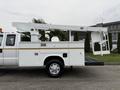 A 2001 Ford F-350 truck with a white utility body and an elevated bucket lift attached to the rear for aerial work