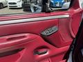 A red interior door panel of a 1995 Ford F-250 featuring power window and lock controls