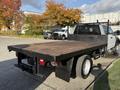 A 2019 Ford F-550 flatbed truck with a wooden bed and black metal sides parked on a lot