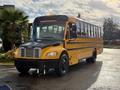 2022 Freightliner B2 school bus with a yellow exterior and black front bumper parked at an angle with large windows and multiple doors on the side