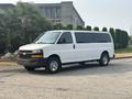 A white 2021 Chevrolet Express van parked on a driveway with a black front grille and chrome accents