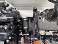 Close-up view of a 2025 Peterbilt 536 engine component featuring various pipes and fittings, including a cylindrical filter and a black lever actuator