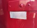 A metal identification plate mounted on a red surface with text detailing the specifications of a GMC C4500 TopKick