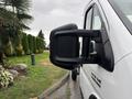 2023 RAM Promaster 3500 side mirror with a textured black finish reflecting nearby greenery and raindrops on the surface