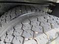 Close-up view of two heavy-duty truck tires with deep treads showcasing wear and debris embedded in the grooves
