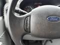 Close-up of a 2013 Ford E-350 steering wheel showcasing controls for turning signals and headlights along with the Ford logo