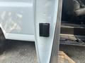 A black door latch mounted on the side of a white 2021 Chevrolet Express van