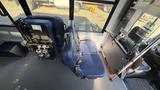 Interior of a 2021 Ford Transit showing two blue seats and a folded wheelchair accessible feature next to the seating area