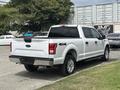 A white 2017 Ford F-150 truck with a crew cab and four-wheel drive parked with its rear facing forward