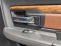 Close-up of the interior door handle of a 2015 RAM 1500 featuring a chrome finish and a wood grain accent with a button for window control