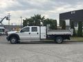 A 2014 Ford F-550 flatbed truck with a dual cab and a metal flatbed attached parked on a concrete surface