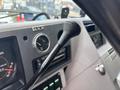 A close-up of the gear shift lever in a 1994 GMC Vandura 3500 dashboard with gauges and controls visible in the background