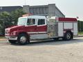 A red and white 1999 Freightliner FL80 fire truck with emergency lights on the roof and various equipment mounted on the side