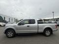 A silver 2015 Ford F-150 pickup truck is shown from the side with four doors and a bed in the back