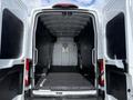 A 2021 Ford Transit rear cargo area with open double doors showing a spacious interior and a partition wall with a ventilation grate