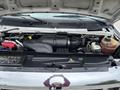 The engine compartment of a 2014 Ford E-350 showing the air intake and various components including hoses and a fluid reservoir