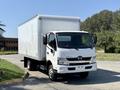 A white 2020 Hino 155 box truck parked with a large cargo area and clear windshield showing the front grille and headlights