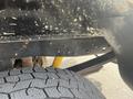 Close-up of the undercarriage of a 2014 Ford F-250 SD showing a metal frame with several drilled holes and a rugged tire tread in the foreground