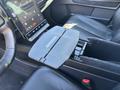 Interior view of a 2023 Fisker Ocean showcasing a touchscreen display and a center console with a flip-top storage compartment