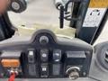 Dashboard controls of a 2012 John Deere 310SJ with switches for various functions and a manual stored behind the panel