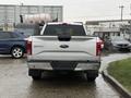 A 2015 Ford F-150 pickup truck viewed from the rear with a silver tailgate and the Ford logo visible on the back