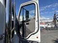 The image shows the open door of a 2022 Freightliner M2 106 revealing a simple interior design with a black handle and a large window