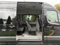 A 2017 Mercedes-Benz Sprinter van with the side door open revealing two rows of seats in the interior