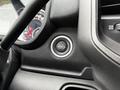 Close-up of the push-to-start engine button in a 2024 RAM 5500 dashboard with a black textured surface and silver ring around the button