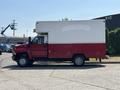 A 2007 GMC C4500 TopKick truck with a red and white box body parked on a lot