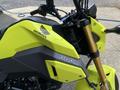 A close-up view of a bright yellow 2018 Honda Grom motorcycle with a prominent logo and sleek design features