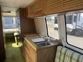 Interior of a 1976 GMC Motorhome featuring wooden cabinetry a small kitchen area with a sink stove and counter space