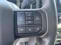 A close-up of a steering wheel control panel in a 2021 Ford F-150 featuring buttons for navigation and media functions